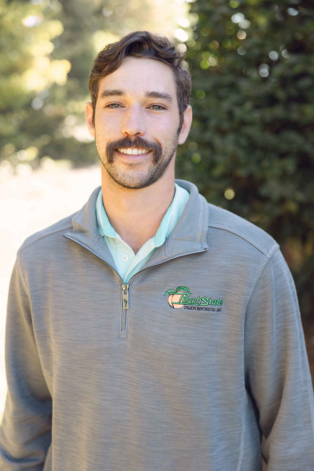 A man with a beard and mustache wearing a gray jacket.