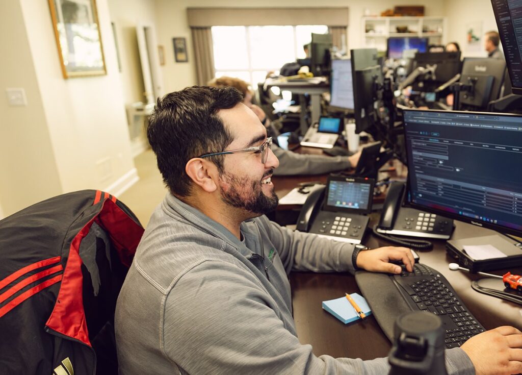 A man sitting at his desk with two laptops.