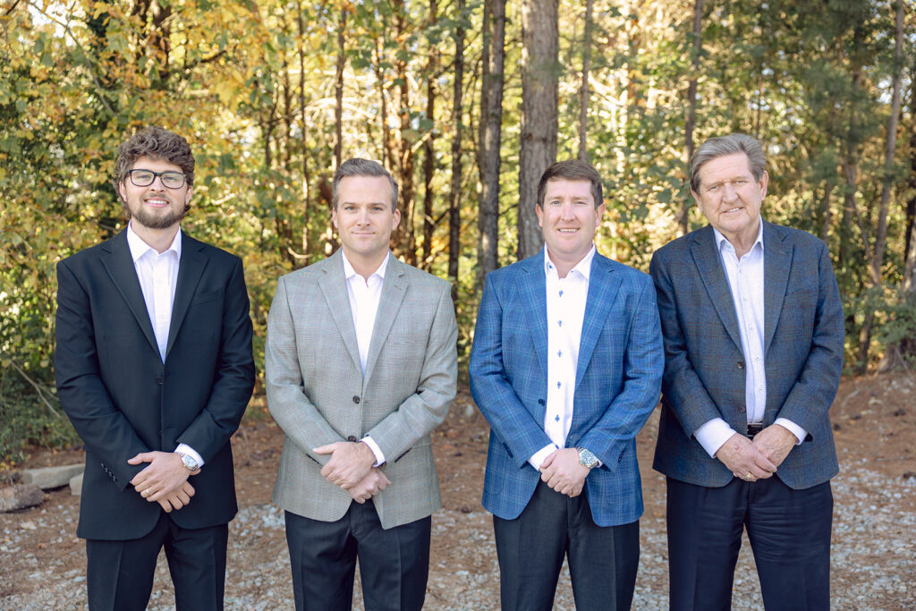 Four men standing in a line wearing suits.