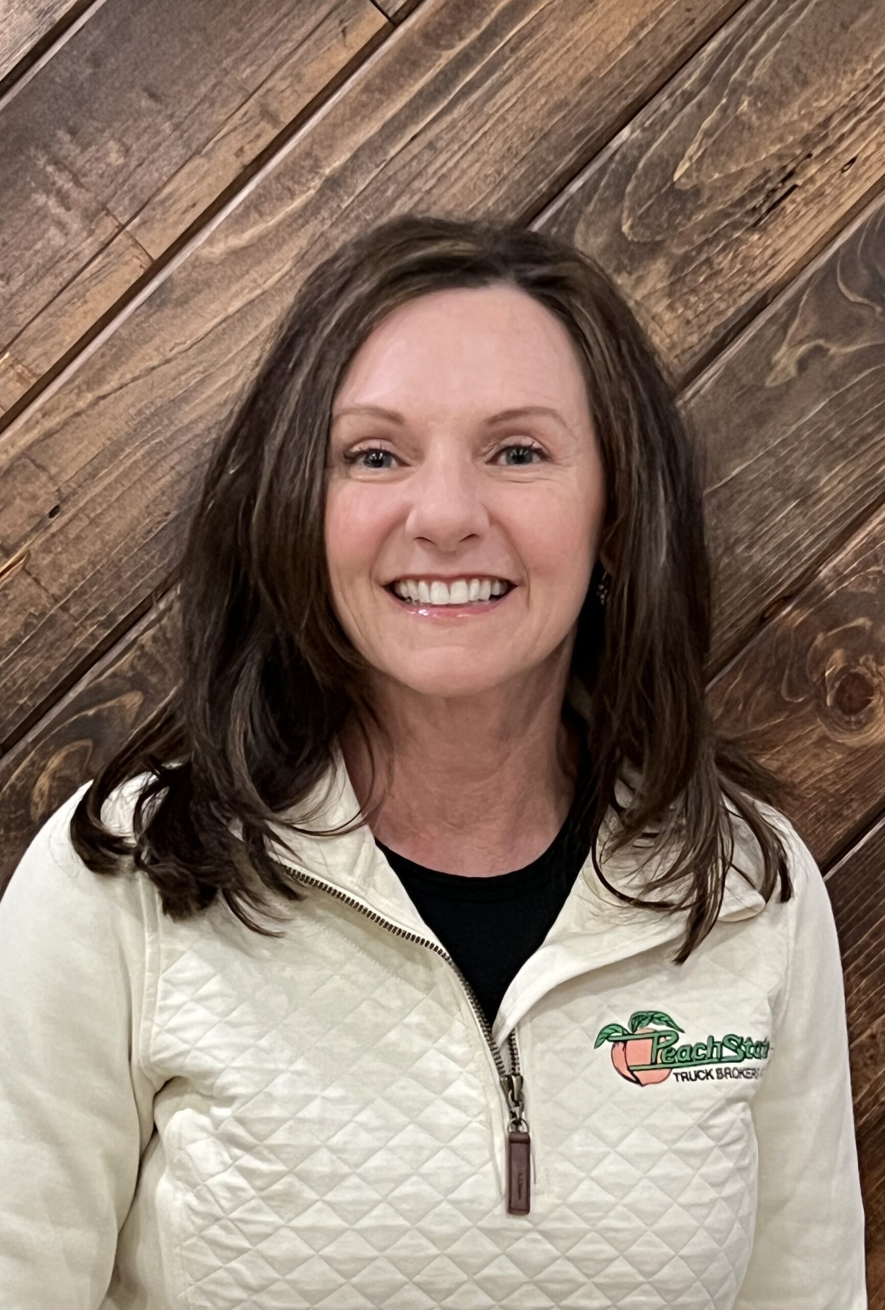 A woman standing in front of a wooden wall.