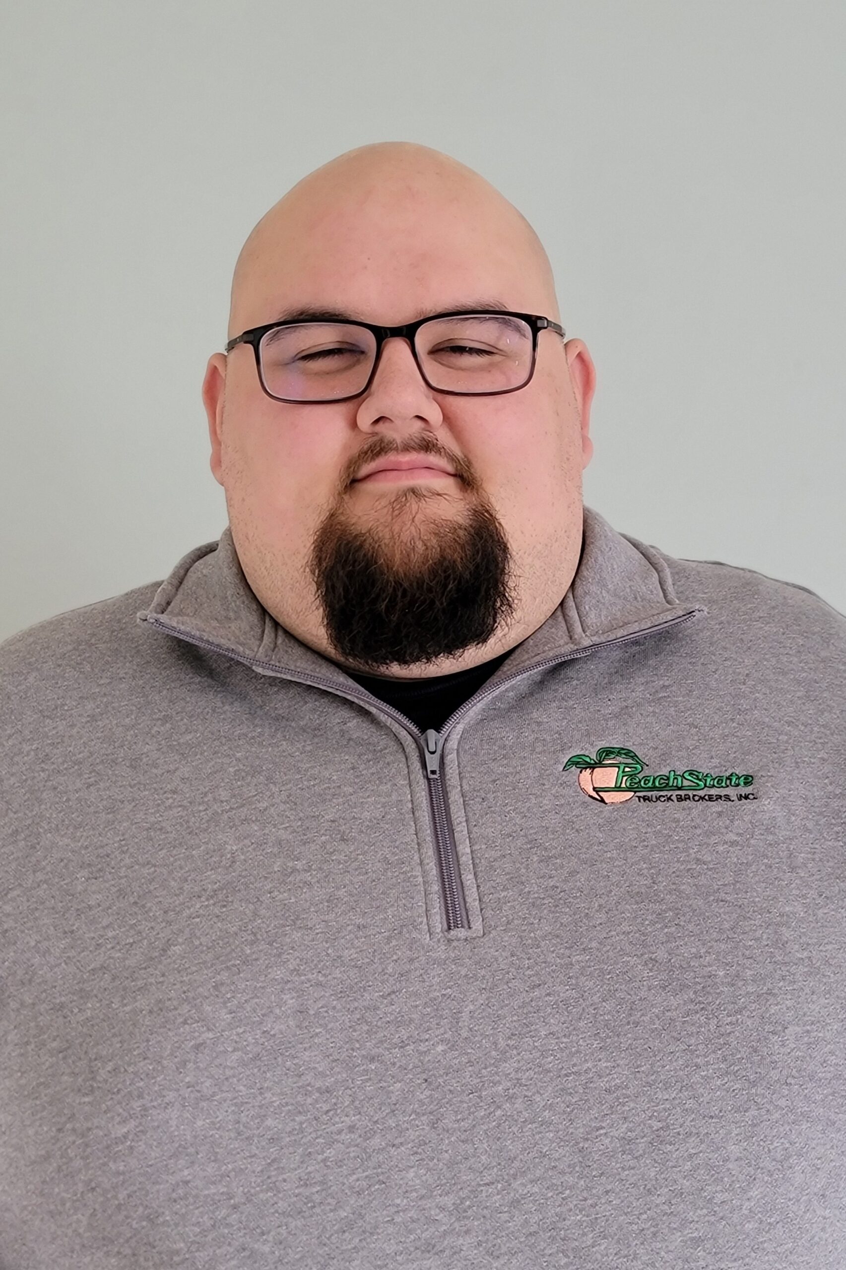 A man with glasses and a beard wearing a gray jacket.