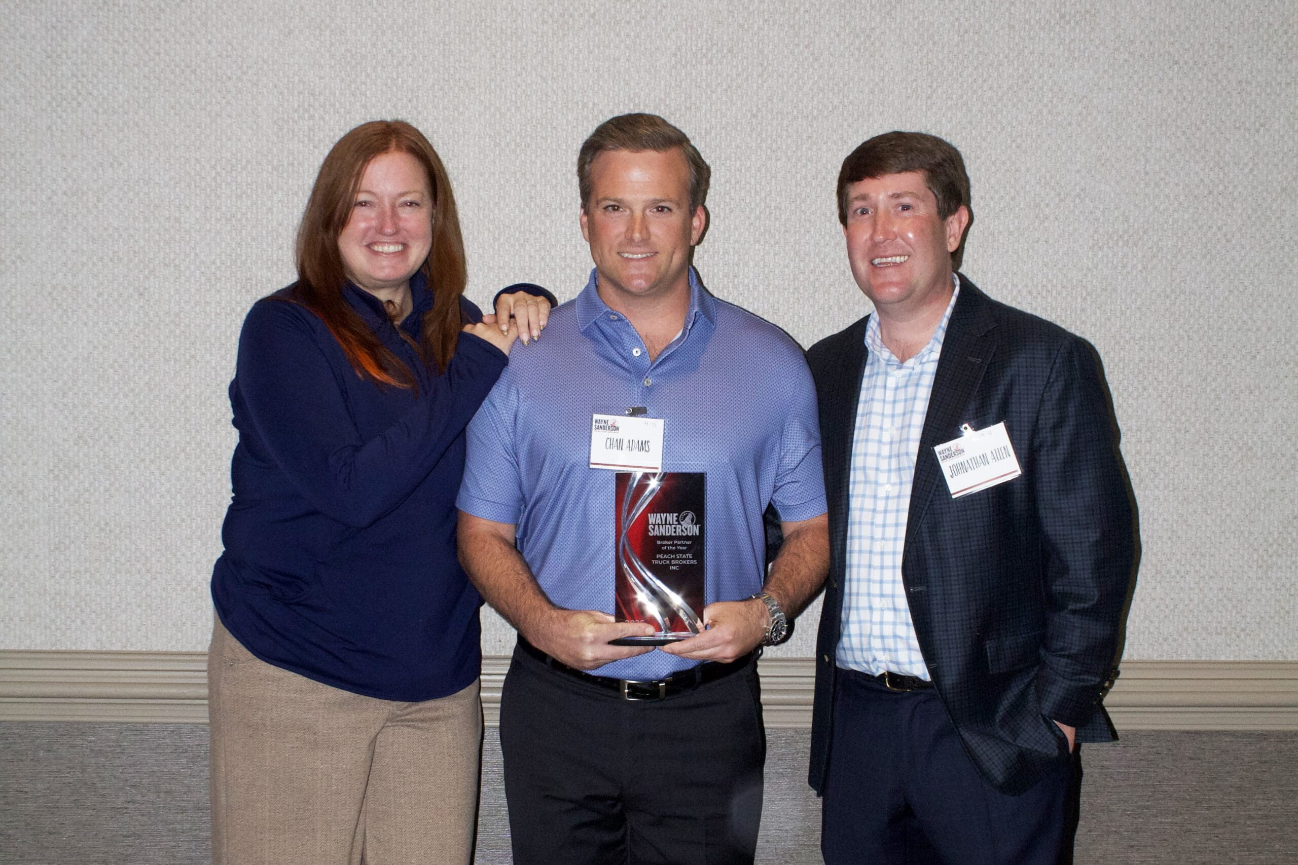 Group portrait of three people holding award